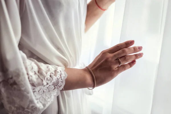 Mañana de la novia, la novia lleva un vestido, una boda, un hermoso vestido, una chica con un bata blanca en la ventana, la chica ata el cinturón en la bata — Foto de Stock