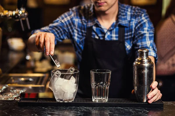 Barmann bei der Arbeit, Barmann gießt harte Spirituosen in Gläser, Barkeeper gießt Tequila ins Glas, bereitet Cocktails zu, Konzept für Service und Getränke — Stockfoto