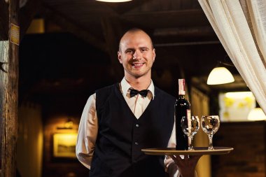 Garson ziyaretçilerin şarap, üniformalı bir emirdir, Garson elini, kendine güvenen garson, bir pub üzerinde beyaz bir havlu ile bekleyen garson sunuyor. Restaurant.Classic.Evening.European Restoran