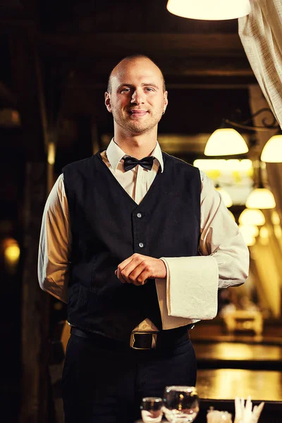 Camarero servido mesa en el restaurante antes de la fiesta, Camarero en uniforme esperando una orden, Camarero con una toalla blanca en la mano, Camarero de confianza — Foto de Stock