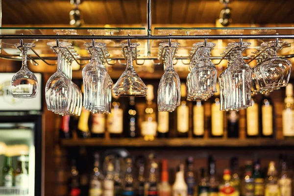 Glasses hanging over a bar rack,Cocktail glasses hanging over a bar,different glasses hanging over the bar. Soft focus,Clean washed and polished glasses,A pub.Bar.Restaurant.