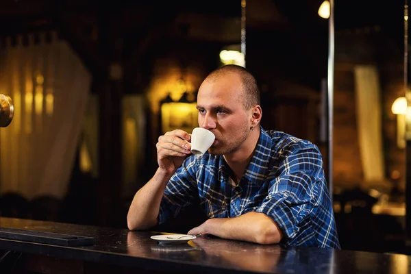 Guapo joven bebiendo café mientras está sentado en el bar counter.enjoying café, Café Cafeína Casual Relajación Estilo Concept.Young hombre de moda bebiendo café expreso en la ciudad café — Foto de Stock