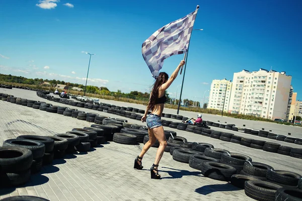 Sexy mujer joven con bandera de racia.Carting árbitro con bandera en Go-kart inicio contra el humo, Go Kart Racer al aire libre con cielo azul — Foto de Stock