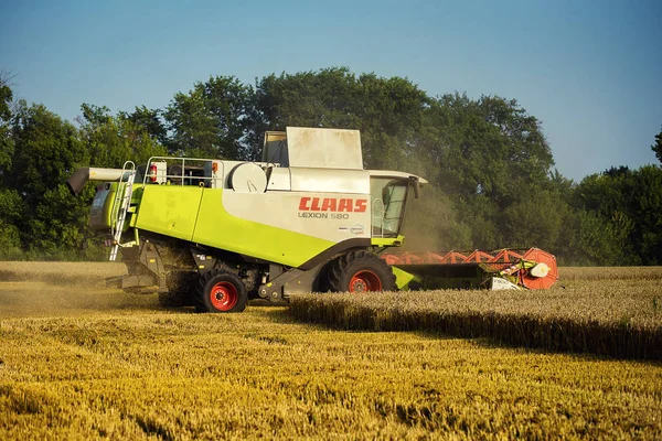 Vinnitsa, Ukrajina-Červenec 27,2016.Grain sklizeň kombinovat, letní krajina nekonečná pole pod modrou oblohou, vykládání zrna, sklizeň pšenice na západ slunce. Zemědělství, práce, příroda a koncepce — Stock fotografie