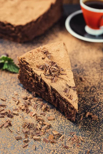 Gâteau au chocolat avec bonbons et tasse de café, gâteau au chocolat avec un morceau coupé et lame sur fond gris, gros plan, gâteau au chocolat noir, gâteau au chocolat végétalien, Gâteau au chocolat savoureux sur fond en bois — Photo