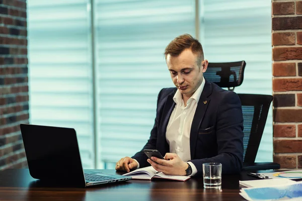 Affärsman hålla en mobiltelefon och skriva sms meddelande i office, affärsman användning smarta mobiltelefon, närbild av en man som använder mobiltelefon, ung affärsman arbetar med moderna enheter mobiltelefon. — Stockfoto