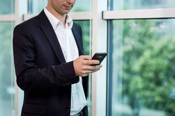 Businessman holding a cell phone and writing sms message in office,businessman use mobile smart phone,Close up of a man using mobile phone,Young businessman working with modern devices mobile phone.