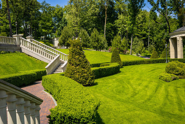 Landscaping in the garden. The path in the garden.Beautiful backyard landscape design,Some flowers and nicely trimmed bushes on the leveled front yard,Landscape formal