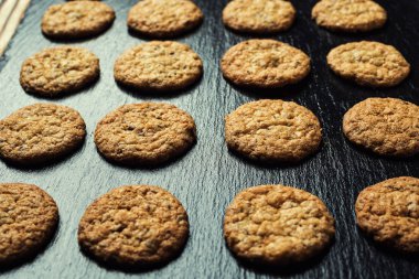 Bisküvi tatlı kurabiye arka plan. Yerli yığılmış tereyağı bisküvi desen kavramı, makro yakından. Ev yapımı kurabiye ahşap masa üzerinde. Mısır gevreği bisküvi susam, yer fıstığı, ayçiçeği ve amaranth.