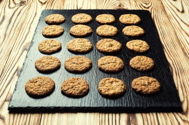 Bisküvi tatlı kurabiye arka plan. Yerli yığılmış tereyağı bisküvi desen kavramı, makro yakından. Ev yapımı kurabiye ahşap masa üzerinde. Mısır gevreği bisküvi susam, yer fıstığı, ayçiçeği ve amaranth.