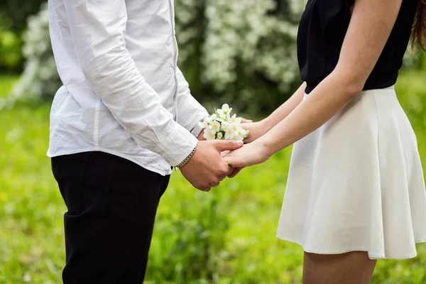 Pasangan di tangan cinta menyentuh bunga, bunga di taman mekar, pasangan tangan memegang bunga di latar belakang kabur hijau, close-up — Stok Foto