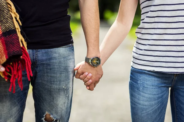 Jovem casal andando no parque e de mãos dadas, Um casal amoroso vai em um piquenique com um tapete — Fotografia de Stock