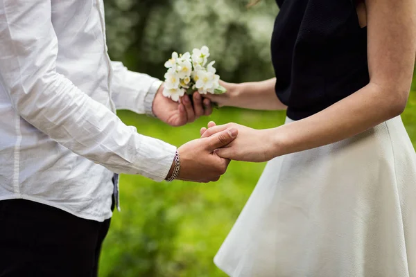 Пара в влюбленных руках трогательный цветок, цветок в саду цветение, пара рук держа цветок на зеленом размытом фоне, крупным планом — стоковое фото