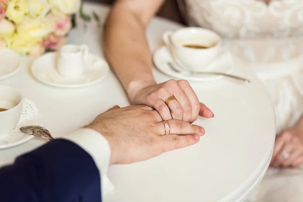 couple holding hands, loving couple drinking coffee in a coffee shop, hands close-up meeting in a cafe, a beautiful bouquet,offee with chocolate candies