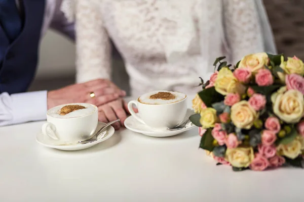 couple holding hands, loving couple drinking coffee in a coffee shop, hands close-up meeting in a cafe, a beautiful bouquet,offee with chocolate candies
