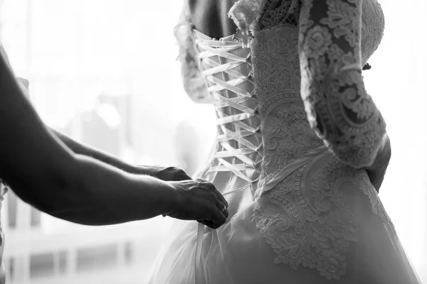 La mañana de la novia, la novia lleva el vestido, la dama de honor corrige el arco en el vestido, la boda, el vestido hermoso —  Fotos de Stock