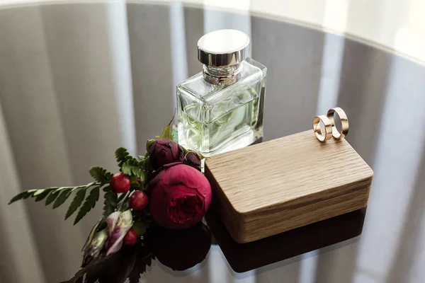 Anéis de casamento jazem na caixa de madeira, acessórios de noiva, casamento europeu, casamento americano, perfume e boutonniere — Fotografia de Stock