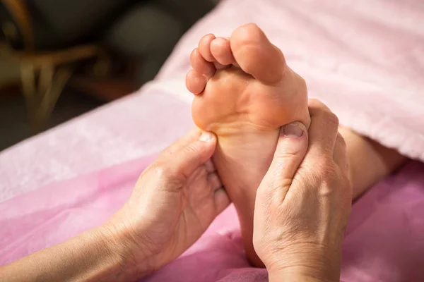 Masaje de pies en el salón de spa, primer plano, Mujer joven teniendo masaje de pies en el salón de belleza, manos femeninas haciendo masaje de pies, Masaje de pies humanos en el salón de spa - Imagen de enfoque suave, tratamiento de pedicura — Foto de Stock