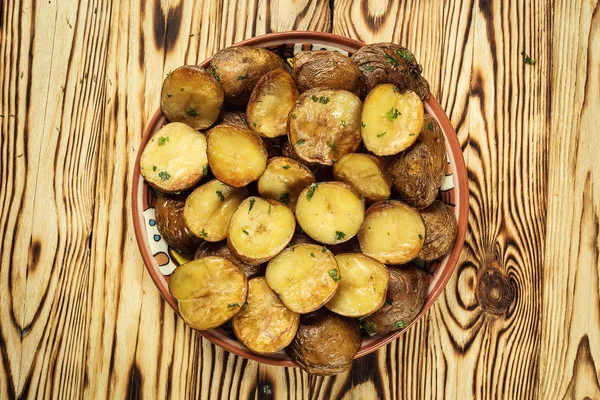 Primo piano di patate cotte al vapore, patate al forno con giacca imburrata calda, patate arrosto in ciotola sul tavolo di legno, patate al forno con sale marino e rosmarino, patate al forno tostate ricoperte di erbe aromatiche . — Foto Stock