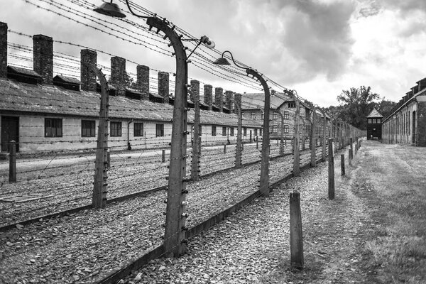 AUSCHWITZ, POLAND - July 11, 2017.Barracks and barbed wire in a concentration camp in Auschwitz (Poland).Museum Auschwitz - Birkenau.Barbed wire around a concentration camp.