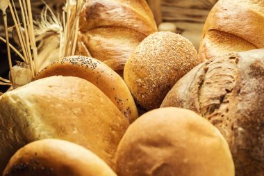 Ekmek sepeti, ahşap masa üzerinde fırın ürün çeşitliliği ile kompozisyon. Ekmek ve buns sepet içinde. Taze ekmek yapım ürünleri masada. Tahıl ürünleri. Ekmek pasta ve bakkal concep