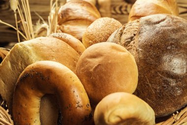 Ekmek sepeti, ahşap masa üzerinde fırın ürün çeşitliliği ile kompozisyon. Ekmek ve buns sepet içinde. Taze ekmek yapım ürünleri masada. Tahıl ürünleri. Ekmek pasta ve bakkal concep