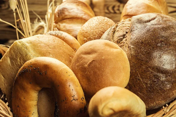 Ekmek sepeti, ahşap masa üzerinde fırın ürün çeşitliliği ile kompozisyon. Ekmek ve buns sepet içinde. Taze ekmek yapım ürünleri masada. Tahıl ürünleri. Ekmek pasta ve bakkal concep
