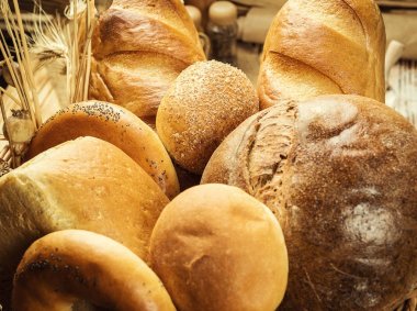 Ekmek sepeti, ahşap masa üzerinde fırın ürün çeşitliliği ile kompozisyon. Ekmek ve buns sepet içinde. Taze ekmek yapım ürünleri masada. Tahıl ürünleri. Ekmek pasta ve bakkal concep