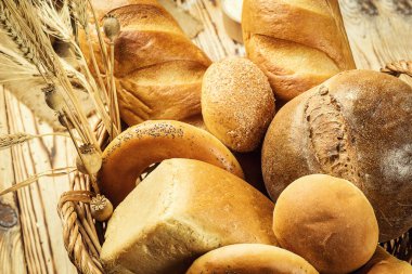 Ekmek sepeti, ahşap masa üzerinde fırın ürün çeşitliliği ile kompozisyon. Ekmek ve buns sepet içinde. Taze ekmek yapım ürünleri masada. Tahıl ürünleri. Ekmek pasta ve bakkal concep