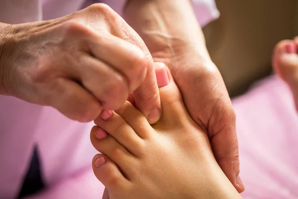 Masaje de pies en el salón de spa, primer plano, Mujer joven teniendo masaje de pies en el salón de belleza, manos femeninas haciendo masaje de pies, Masaje de pies humanos en el salón de spa - Imagen de enfoque suave, tratamiento de pedicura — Foto de Stock