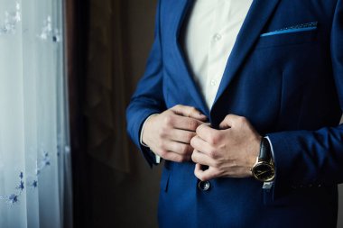 İş adamı ceket giyiyor, erkek eli kapalı, damat düğün töreninden önce hazırlanıyor.