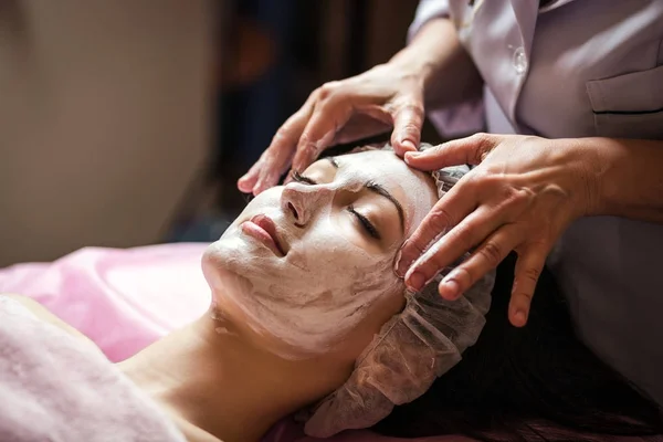Mujer recibiendo cuidado facial mascarilla peladora por esteticista en el salón de spa —  Fotos de Stock