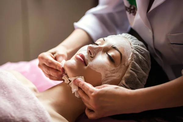 Mujer recibiendo cuidado facial mascarilla peladora por esteticista en el salón de spa —  Fotos de Stock