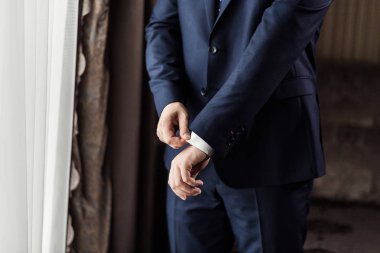 İş adamı ceket giyiyor, erkek eli kapalı, damat düğün töreninden önce hazırlanıyor.