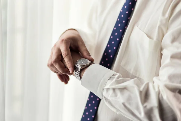 Geschäftsmann, der die Uhrzeit an seiner Armbanduhr überprüft, Mann, der die Uhr an der Hand hält, Bräutigam, der morgens vor der Trauung fertig wird — Stockfoto