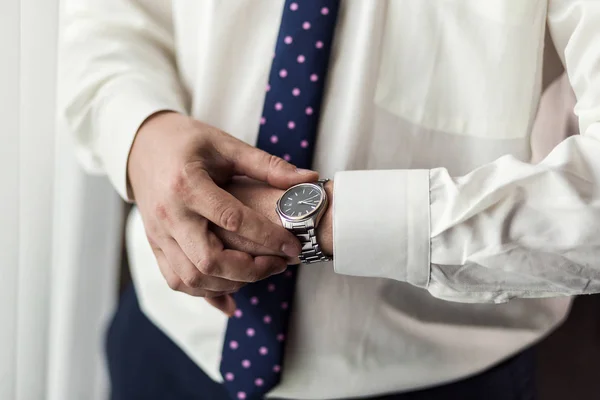 Uomo d'affari controllare il tempo sul suo orologio da polso, l'uomo mettendo orologio a portata di mano, sposo si prepara al mattino prima della cerimonia di matrimonio — Foto Stock