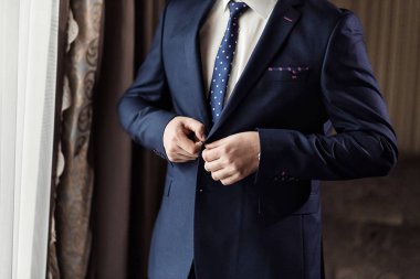 İş adamı ceket giyiyor, erkek eli kapalı, damat düğün töreninden önce hazırlanıyor.