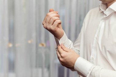 İş adamı beyaz gömlek giyer, erkek eli yakın durur, damat düğün töreninden önce sabah hazırlanır.