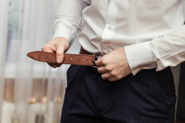 İş adamı kemer takıyor, moda ve giysi konsepti, damat törenden önce sabah hazırlanıyor.