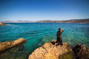 Hasır şapka tutan ve bir mavi denize bakarak elbiseli kadın