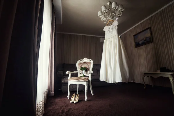 Belle robe de mariée suspendue dans la chambre, femme se préparer avant la cérémonie — Photo