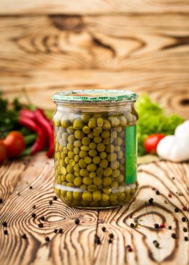 Kompozisyon kavanoz ve malzemeler ahşap arka plan üzerinde turşu yeşil bezelye