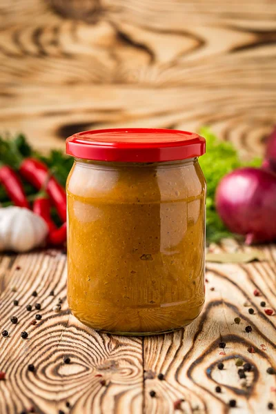 Composition of squash caviar in jar and ingredients on wooden background