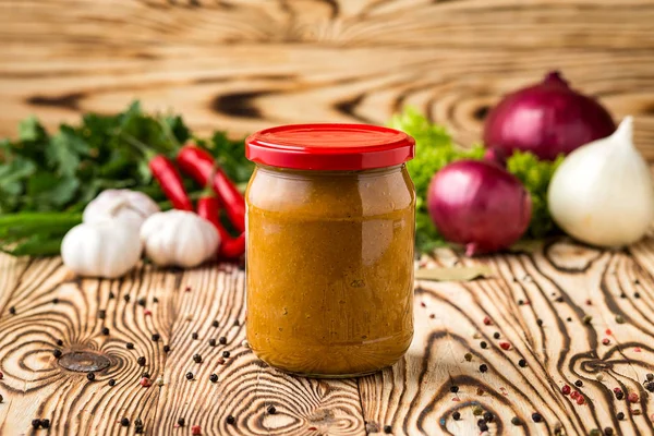 Composition of squash caviar in jar and ingredients on wooden background