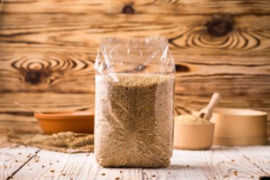 Ambalaj ve kase ahşap arka plan üzerinde buğday kabuğu çıkarılmış tane. Sağlıklı Diyet hububat kavramı.