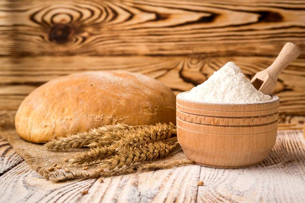 Bread with wheat flour, spikes and grains on wooden table. Agriculture and harvest concept. — Stock Photo, Image