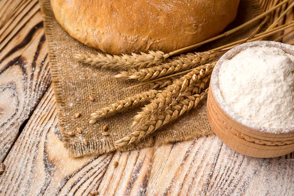Хліб з пшеничним борошном, шипами і зернами на дерев'яному столі. Концепція сільського господарства та збору врожаю . — стокове фото
