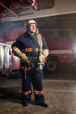 İtfaiyeci (itfaiye) yakınındaki bir firetruck haddelenmiş yangın hortumu ile eylem. Acil durum Emanet. Koruma, tehlikeden kurtarmak.