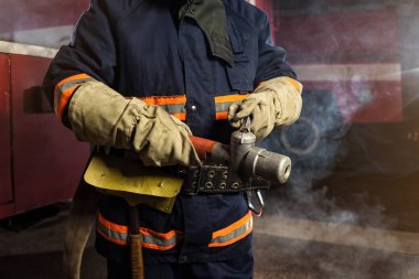 İtfaiyeci (itfaiye) yakınındaki bir firetruck haddelenmiş yangın hortumu ile eylem. Acil durum Emanet. Koruma, tehlikeden kurtarmak.