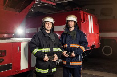 İtfaiyeci (itfaiye) eylem daimi bir firetruck yakınındaki. Acil durum Emanet. Koruma, tehlikeden kurtarmak.
